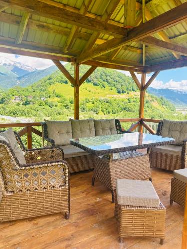 a porch with a couch and chairs and a table at Mountain Shadow Cottage in Racha in Ghebi