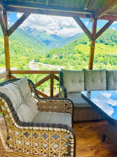 a porch with a couch and a table and mountains at Mountain Shadow Cottage in Racha in Ghebi