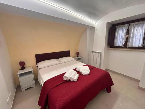 a bedroom with a bed with towels on a red blanket at B&B dell'Arco in LʼAquila