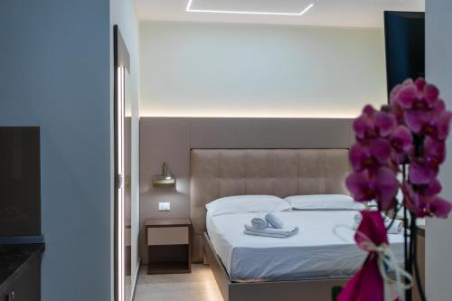 a bedroom with a bed and purple flowers in a vase at The Reserve by Vulcano in Mirto