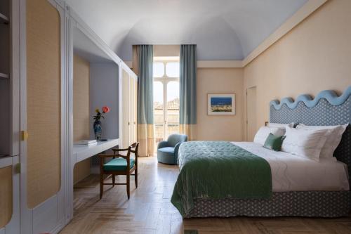 a bedroom with a bed and a desk and a window at EGEO - Ortigia in Syracuse