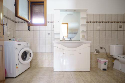 a bathroom with a sink and a washing machine at Sagiada Anchor House in Sagiada