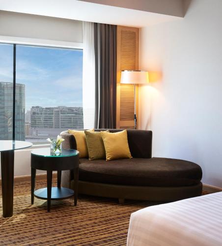 a hotel room with a couch and a window at Amari Bangkok in Bangkok