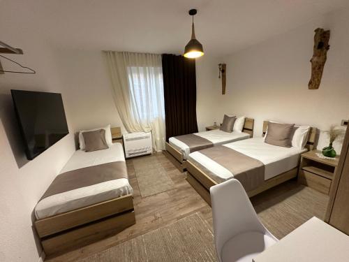 a hotel room with two beds and a flat screen tv at Mosaic Guesthouse in Lin