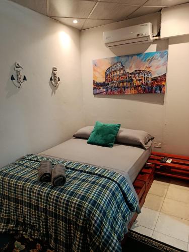 a bedroom with a bed and a painting on the wall at Hostal Cigarra in Panama City