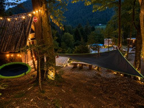 a tent and a hammock in a forest at night at Mornov raj in Vuzenica