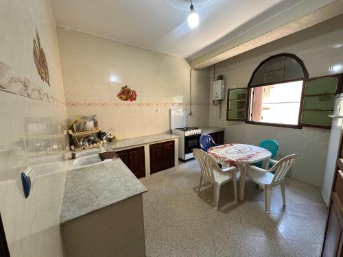 a kitchen with a table and a table and chairs at el sahel residence in Beni Haoua