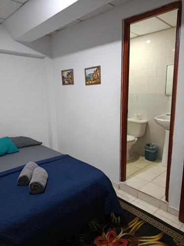 a bedroom with a bed and a bathroom with a mirror at Hostal Cigarra in Panama City