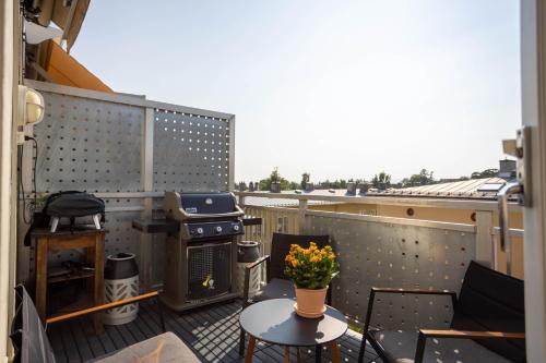 a balcony with a stove and a table with flowers at Modern 3 bedroom apartment - 4 minute walk from metro - top floor baclony view in Oslo
