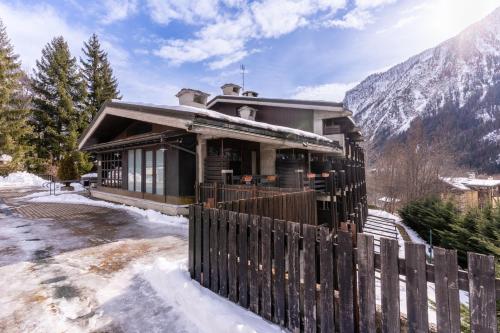 a house with a fence in the snow at Hotel Les Jumeaux Courmayeur in Courmayeur