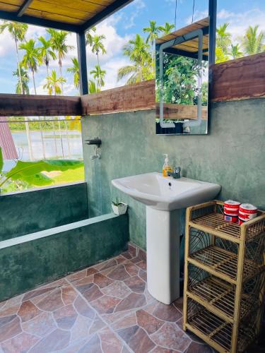 a bathroom with a sink and a tub and a mirror at Jungle Lake View Cabana in Udawalawe