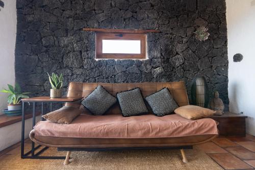 a couch in a room with a stone wall at Tabaiba Suites Lanzarote - Macaronesia Homes in La Asomada