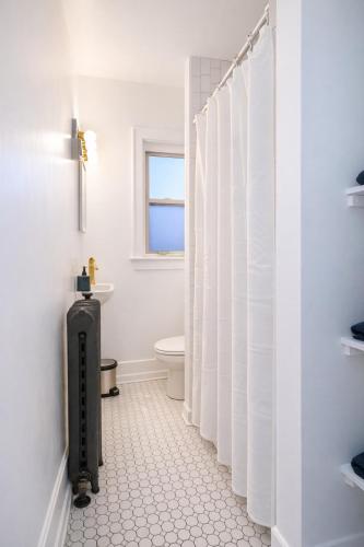 a white bathroom with a toilet and a suitcase at Downtown High Falls Studio Apt, Kitchen, TV in Rochester