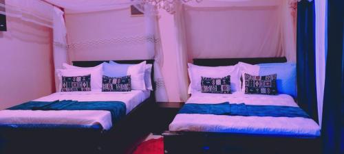 two beds in a room with pink and blue at SolBlu Cottages in Kira