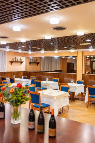 a restaurant with white tables and blue chairs and flowers at Hotel Les Jumeaux Courmayeur in Courmayeur
