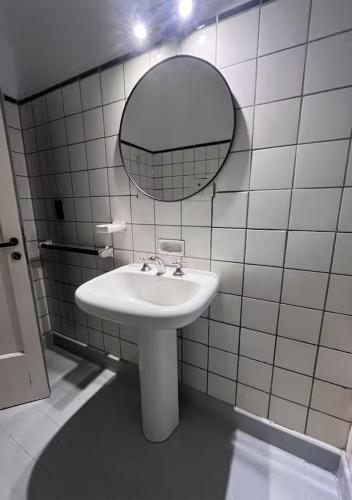 a white tiled bathroom with a sink and a mirror at Lomar suite 2 - Depto céntrico Villa María in Villa María