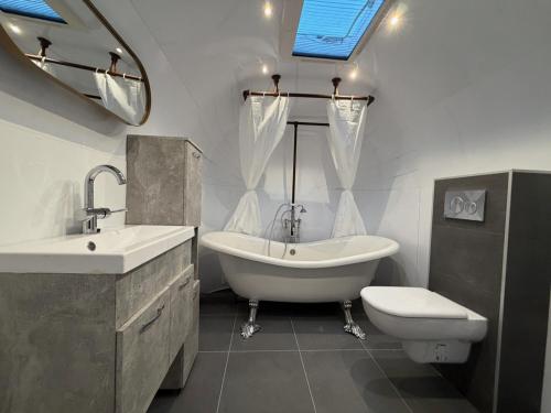 a bathroom with a tub and a sink and a toilet at Tin Can Town Oirschot in Oirschot