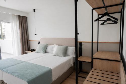 a bedroom with a bed with white sheets and blue pillows at AR Roca Esmeralda & SPA Hotel in Calpe