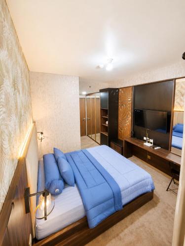 a bedroom with a large blue bed and a television at Transpark Cibubur by 21room in Kalimanggis