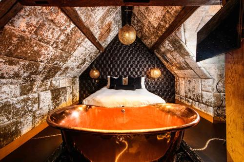 a bath tub in a room with a bed at Crazy Bear Beaconsfield in Beaconsfield