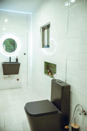 a white bathroom with a toilet and a sink at Résidence Daana in Komé