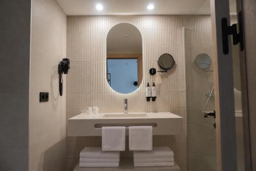 a bathroom with a sink and a mirror and towels at AR Roca Esmeralda & SPA Hotel in Calpe