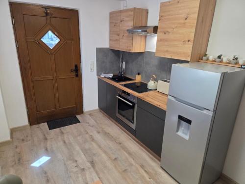a kitchen with a white refrigerator and a wooden door at Apartment Linde in Bubesheim
