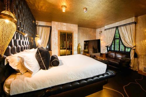a bedroom with a large bed and a leather couch at Crazy Bear Beaconsfield in Beaconsfield