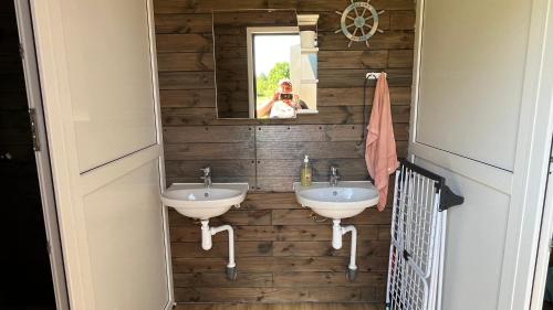 a woman taking a picture of a bathroom with two sinks at Peipsi Village Sofia in Kasepää