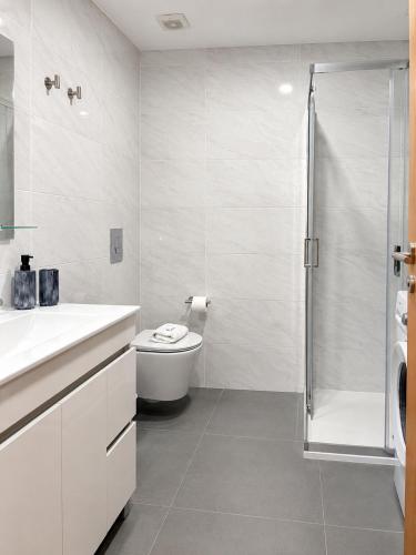 a white bathroom with a toilet and a shower at Dona Emília Mercado in Viana do Castelo