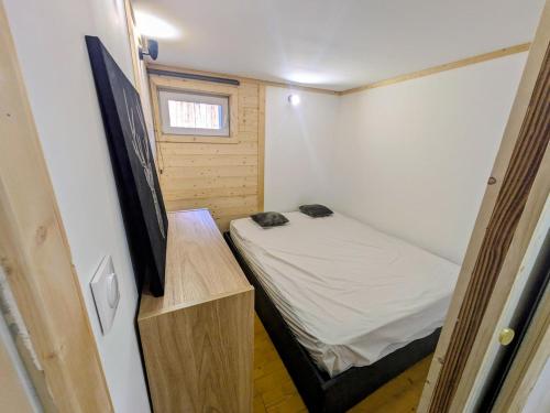 a small bedroom with a bed and a flat screen tv at Nice chaleett in mountains in Saint-Martin-de-Belleville