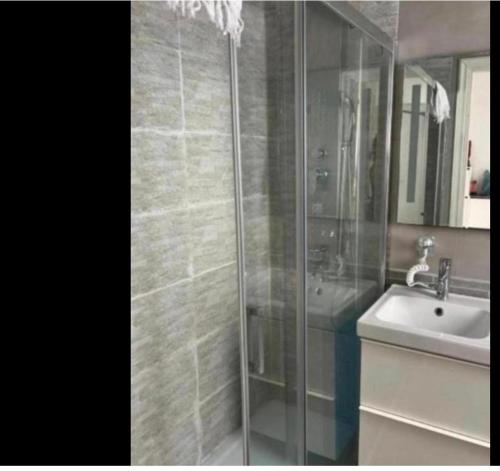 a bathroom with a glass shower and a sink at Spina home in Vieste