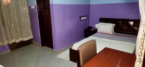a purple room with a bed and a table at NHYIRA Hotel in Sekondi-Takoradi