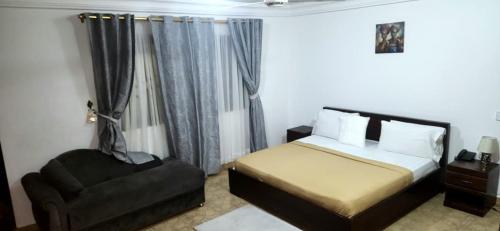 a bedroom with a bed and a chair at NHYIRA Hotel in Sekondi-Takoradi