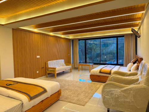 a bedroom with two beds and a large window at Pine View Hotel in Abbottabad