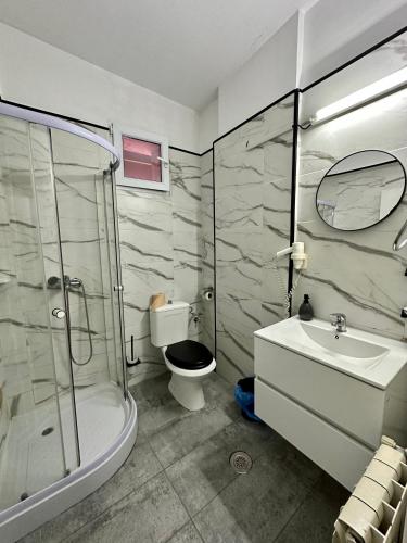 a bathroom with a toilet and a sink and a shower at Dallin Center Hotel in Bucharest