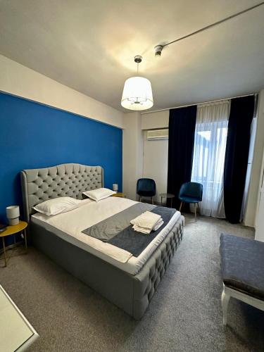a bedroom with a large bed with a blue wall at Dallin Center Hotel in Bucharest