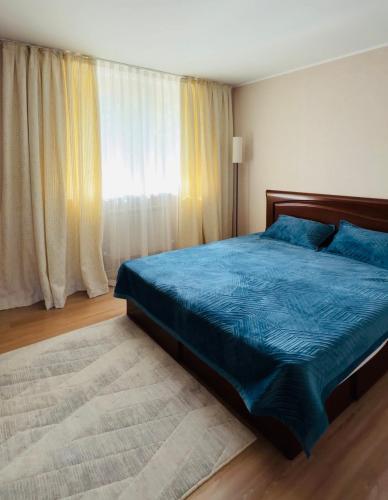 a bedroom with a blue bed and a window at Пар&Речка in Almaty