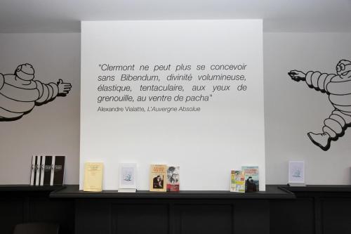 a wall with two posters on it with books on it at Hotel Litteraire Alexandre Vialatte, BW Signature Collection in Clermont-Ferrand