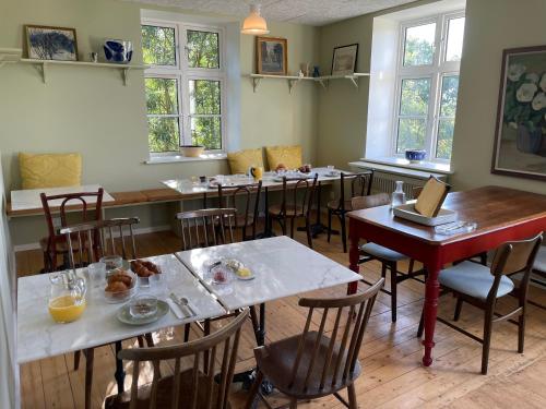 a dining room with tables and chairs and windows at Roholtegaard in Faxe