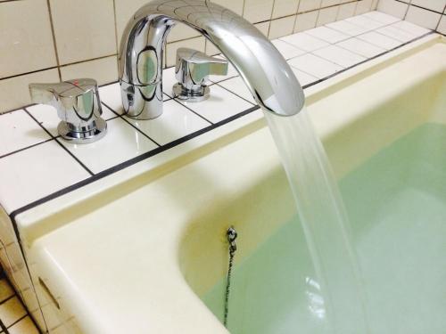 a sink with water coming out of a faucet at Miyoshiya Ryokan in Tanabe