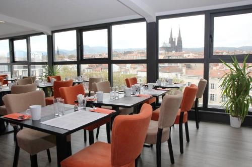 a restaurant with tables and chairs and large windows at Hotel Litteraire Alexandre Vialatte, BW Signature Collection in Clermont-Ferrand