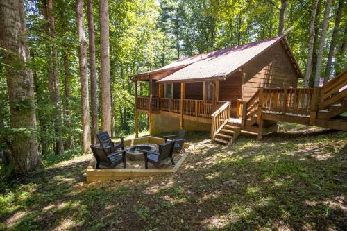 a log cabin in the woods with a deck and chairs at Fox Trail Cabin in Boone