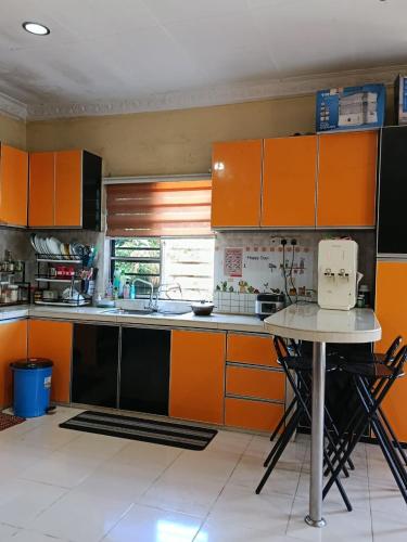a kitchen with orange cabinets and a table in it at Villa Cempaka II in Changlun