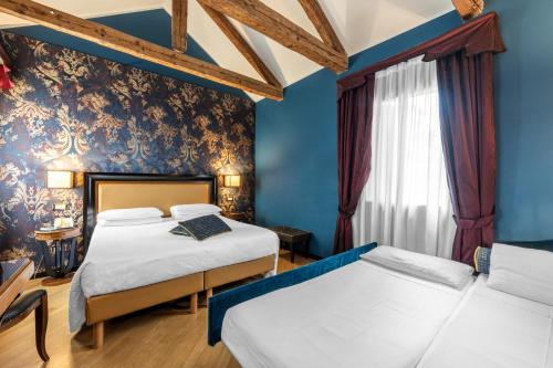 two beds in a room with blue walls at Hotel Paganelli in Venice