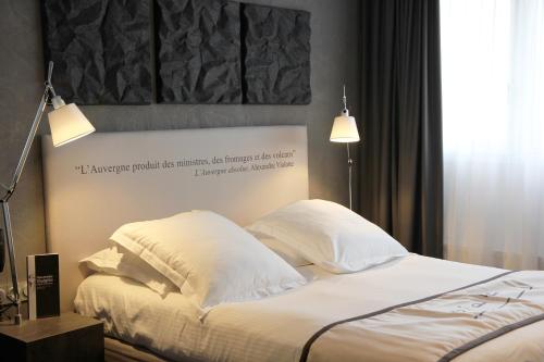 a bedroom with a bed with white sheets and pillows at Hotel Litteraire Alexandre Vialatte, BW Signature Collection in Clermont-Ferrand
