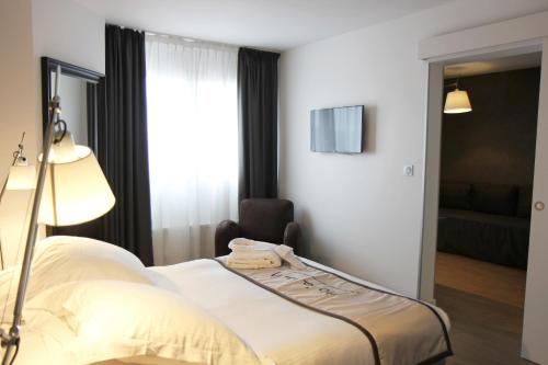 a hotel room with a bed and a television at Hotel Litteraire Alexandre Vialatte, BW Signature Collection in Clermont-Ferrand