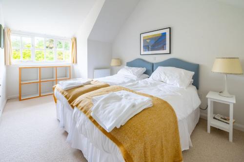a bedroom with a large bed with white sheets at Flint Cottage, Brancaster in Brancaster