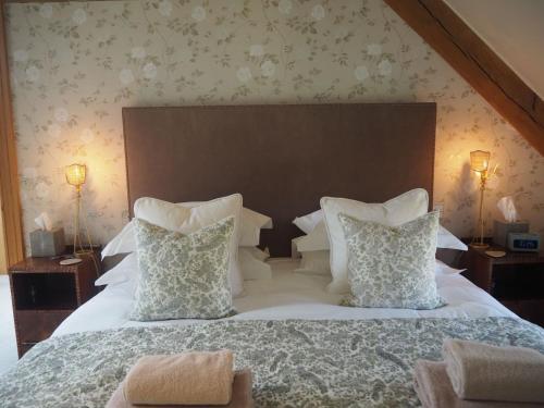 a bedroom with a large white bed with two pillows at Hobbs Hole Cottage in Great Tew
