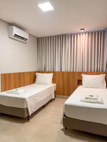 a bedroom with two beds and a window at Uai Hotel Jaíba in Terra Fôfa